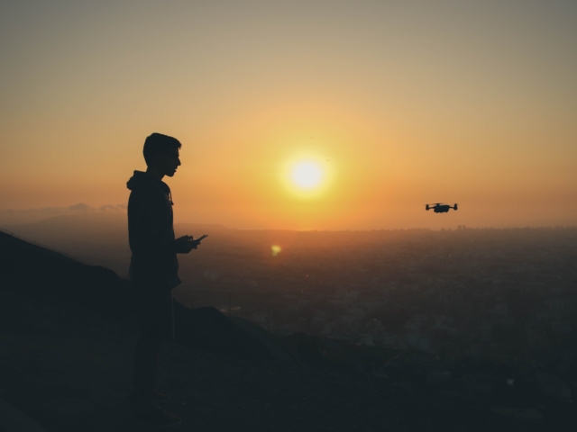 Man flying drone at sunset