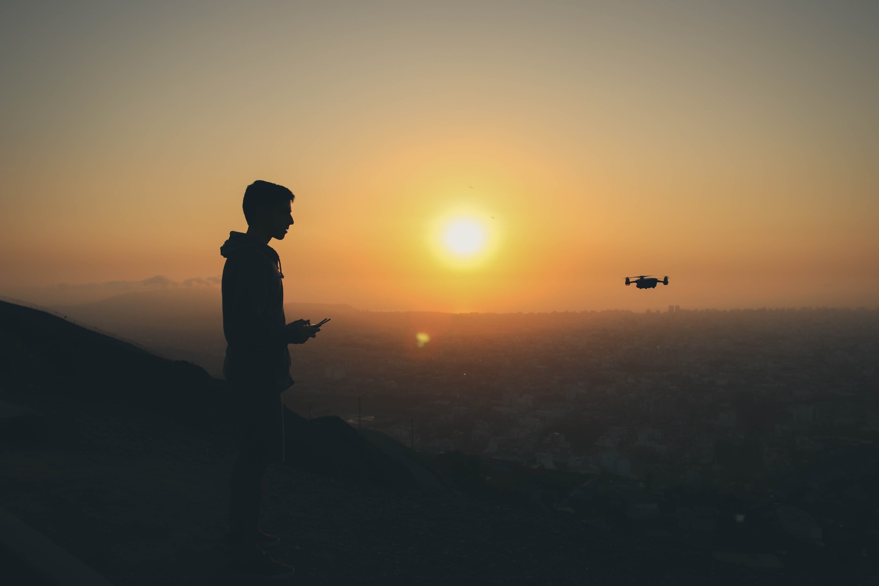 Man flying drone at sunset